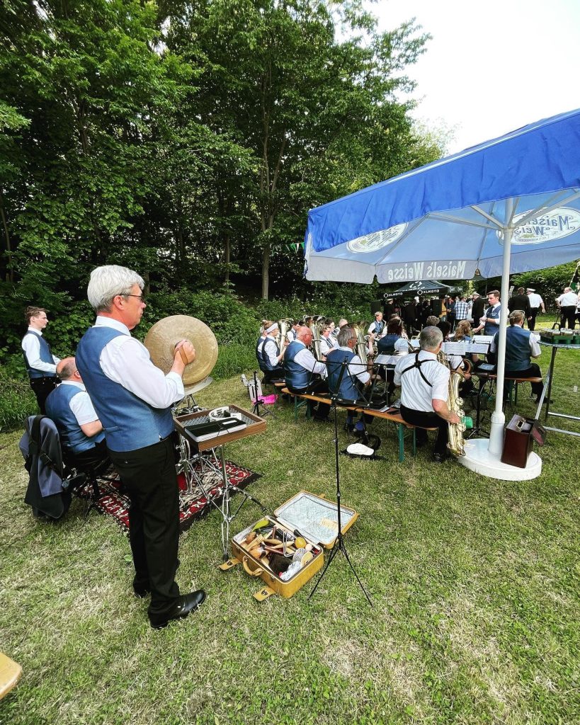 Ein Musiker mit Becken, dahinter das Orchester im Freien, Sommerfest des GVU Hüsten 2022