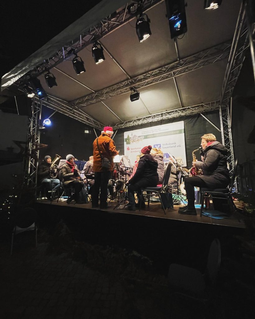 Der Dirigent mit roter Mütze leitet das Orchester auf dem Weihnachtsmarkt 2022