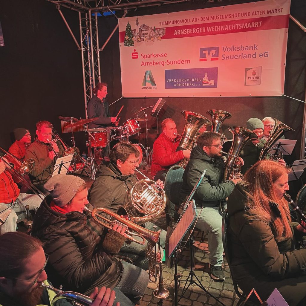 Musikerinnen und Musiker mit Weihnachtsmützen auf der Weihnachtsmarktbühne 2023