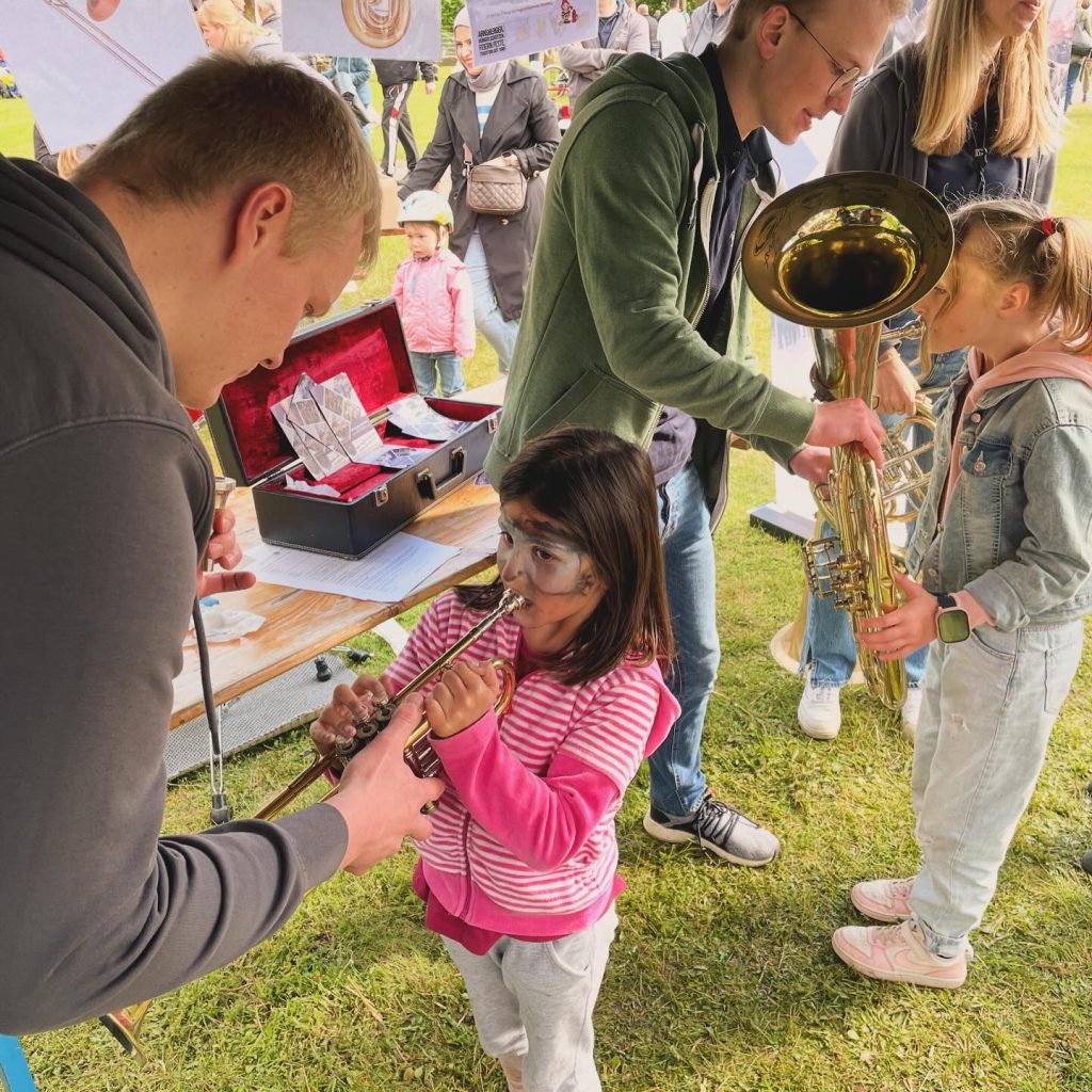 Ein Mädchen probiert mit Anleitung die Trompete aus, Kids Day 2024
