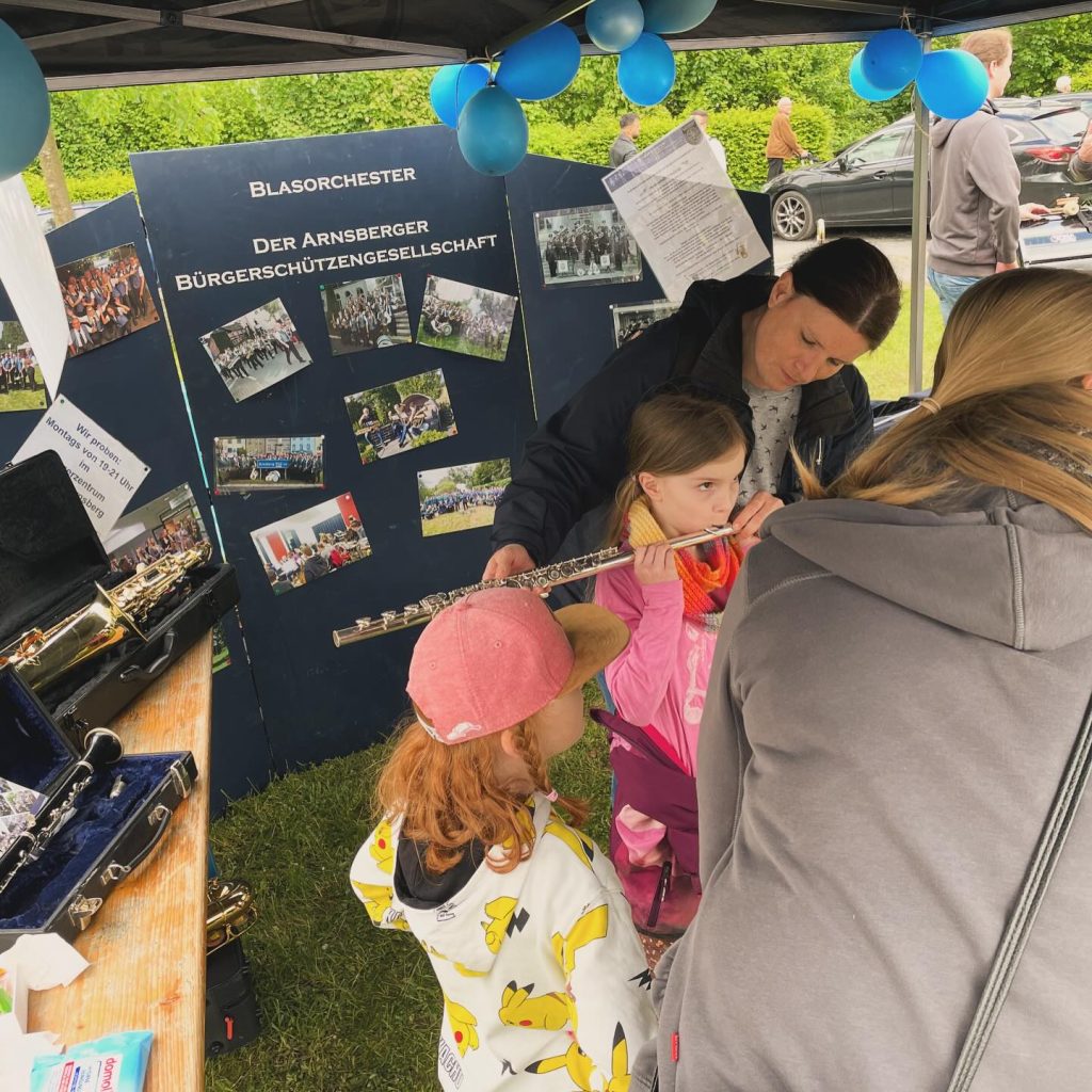 Kinder am Infostand mit Fotowand des Blasorchesters beim Kids Day 2024