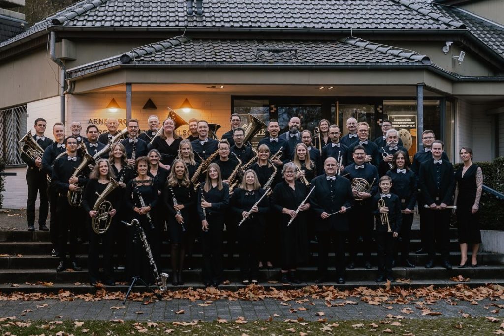 Gruppenfoto des Blasorchesters vor der Festhalle am Tag des Herbstkonzerts „Horizonte und Helden“ 2025